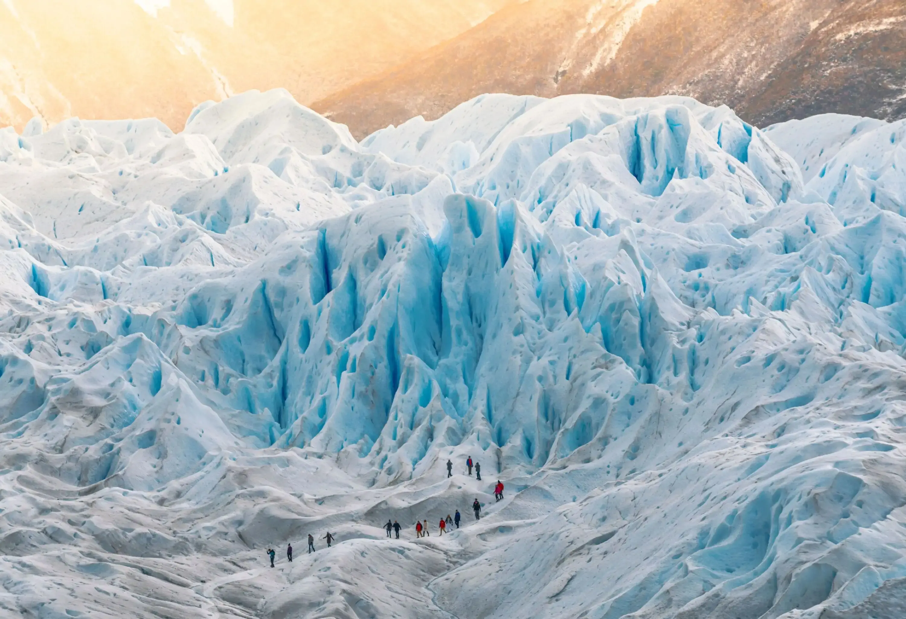 People walk in a line along a glacier's fascinating ice formations.