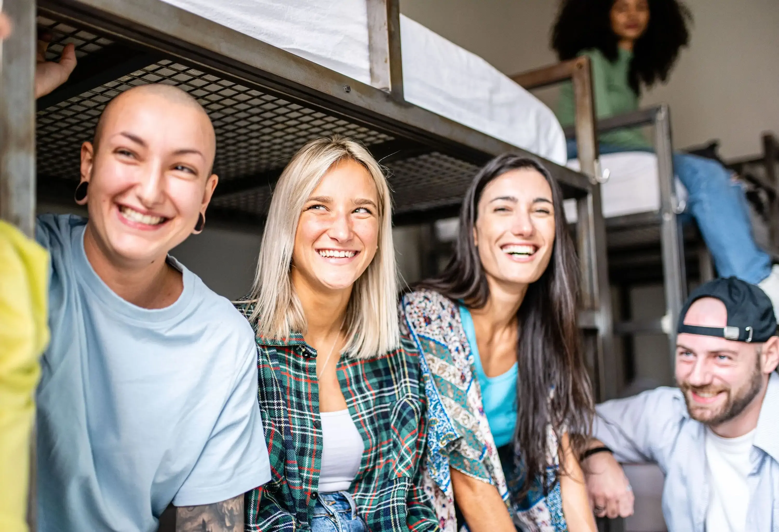 A group of friends happily sits back inside their hostel room.