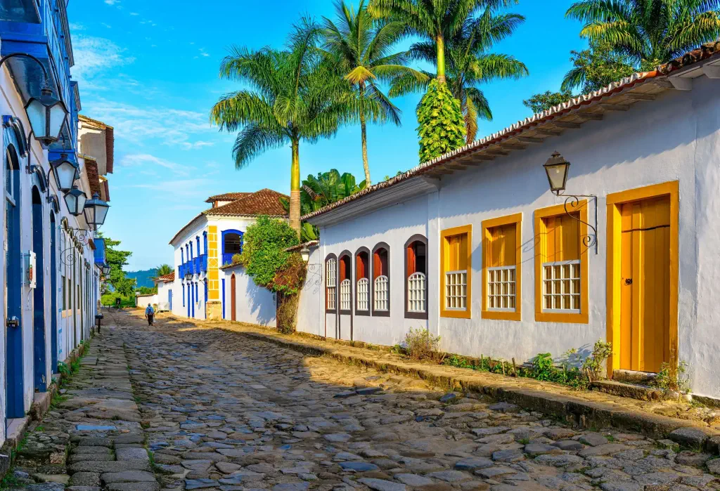 A lone man walking through the cobbled street between the colourful traditional houses.