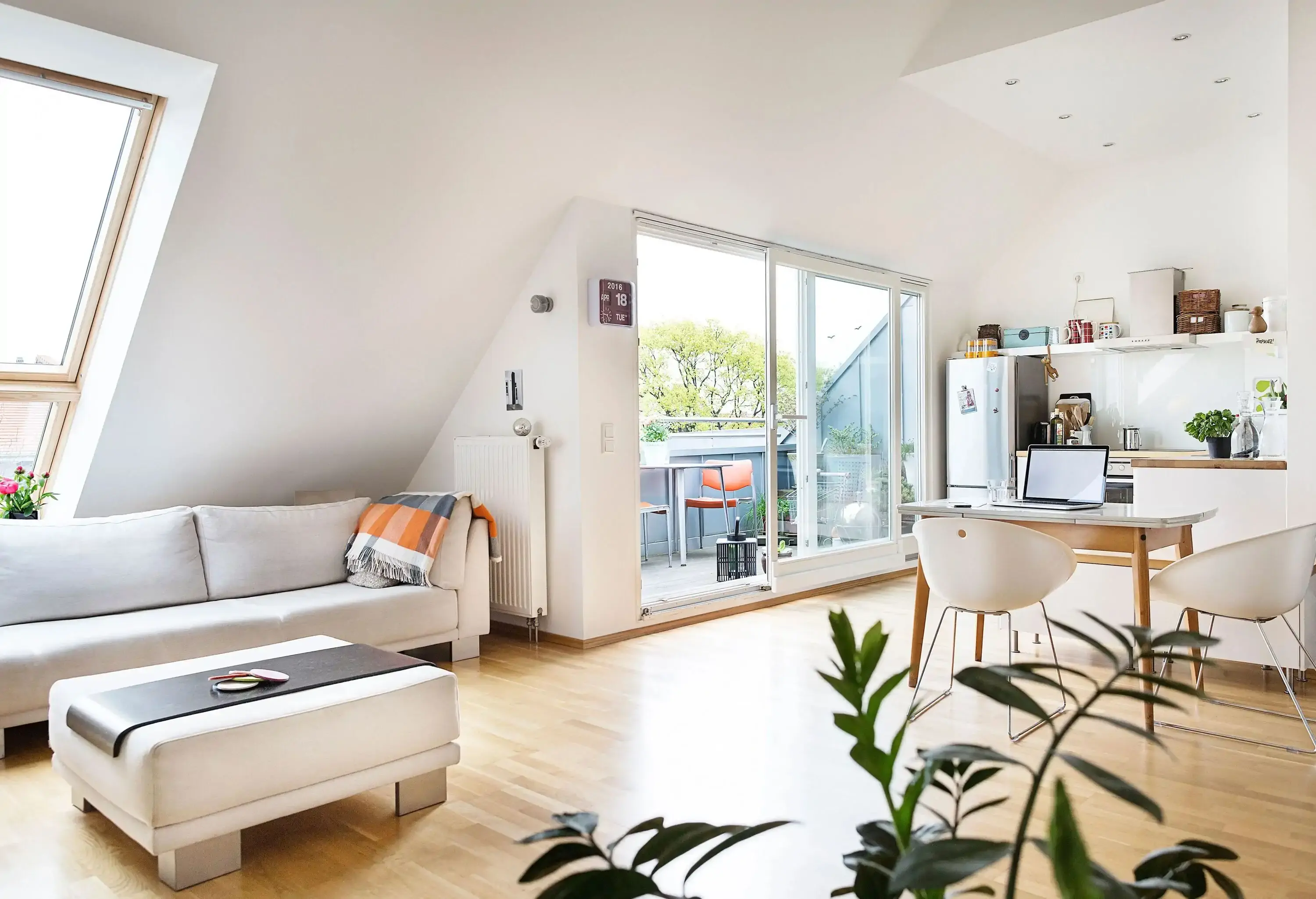 A modern-designed living room and dining room seamlessly blend together, with a glass door leading to a balcony, allowing abundant natural light to flood the space while offering a seamless connection between the indoor and outdoor areas.