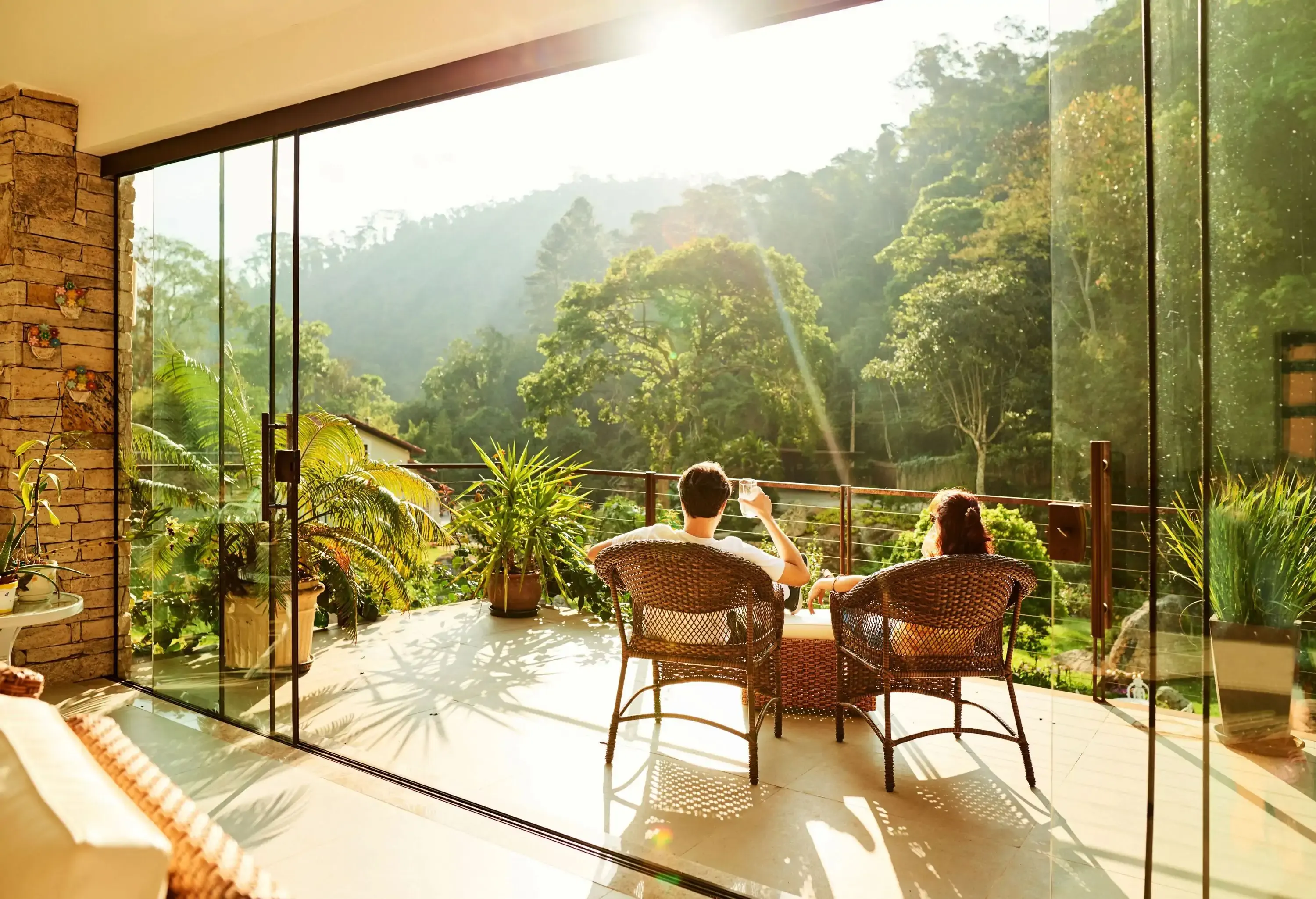 A couple sitting on the balcony watching the scenic nature view with refreshing drinks.