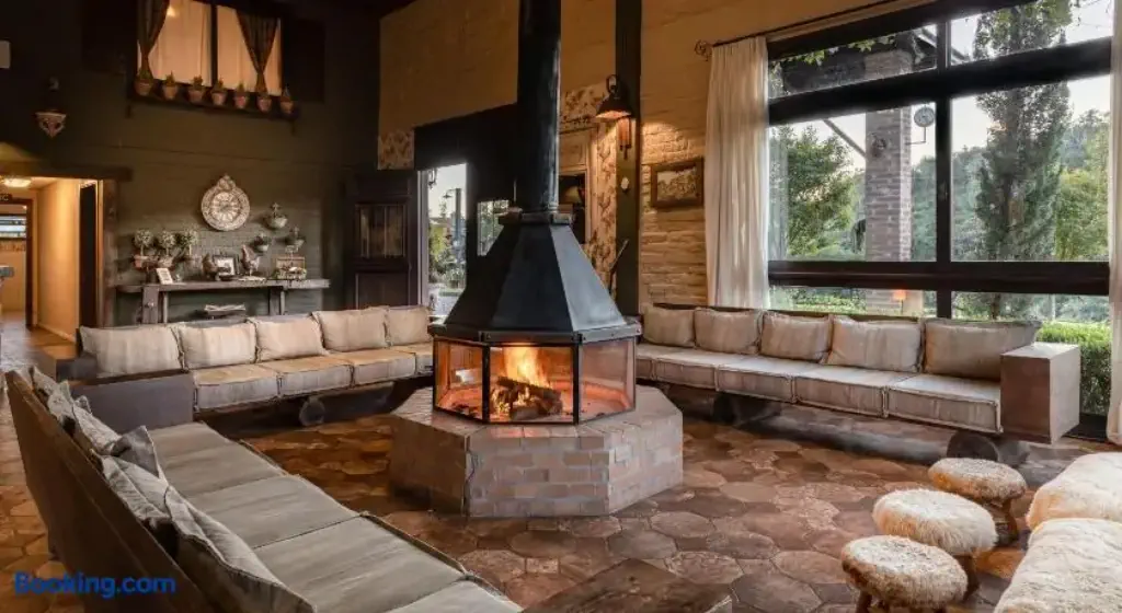 Rustic lobby of a farmhouse hotel with roaring fire pit in the middle of the room