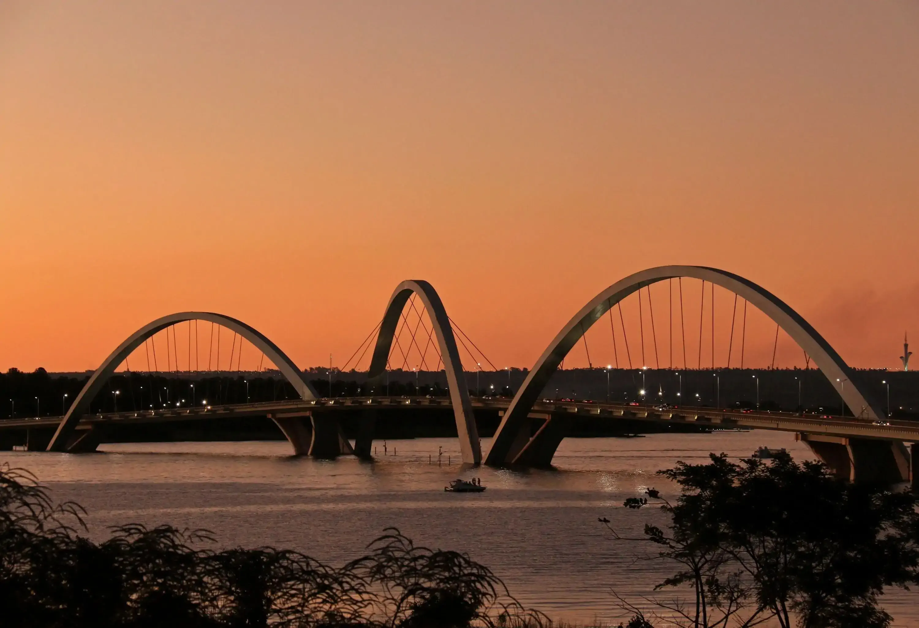 The Juscelino Kubitschek Bridge, a modern marvel of engineering, features three graceful arches that elegantly span the distance, supported by iron cables that add both strength and aesthetic appeal.