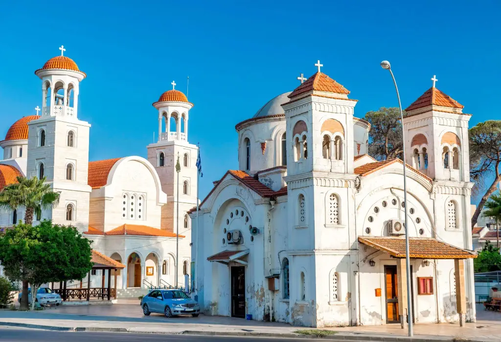 Two white churches with twin bell towers each, one with red tile hip roofs and the other with red tile dome roofs.