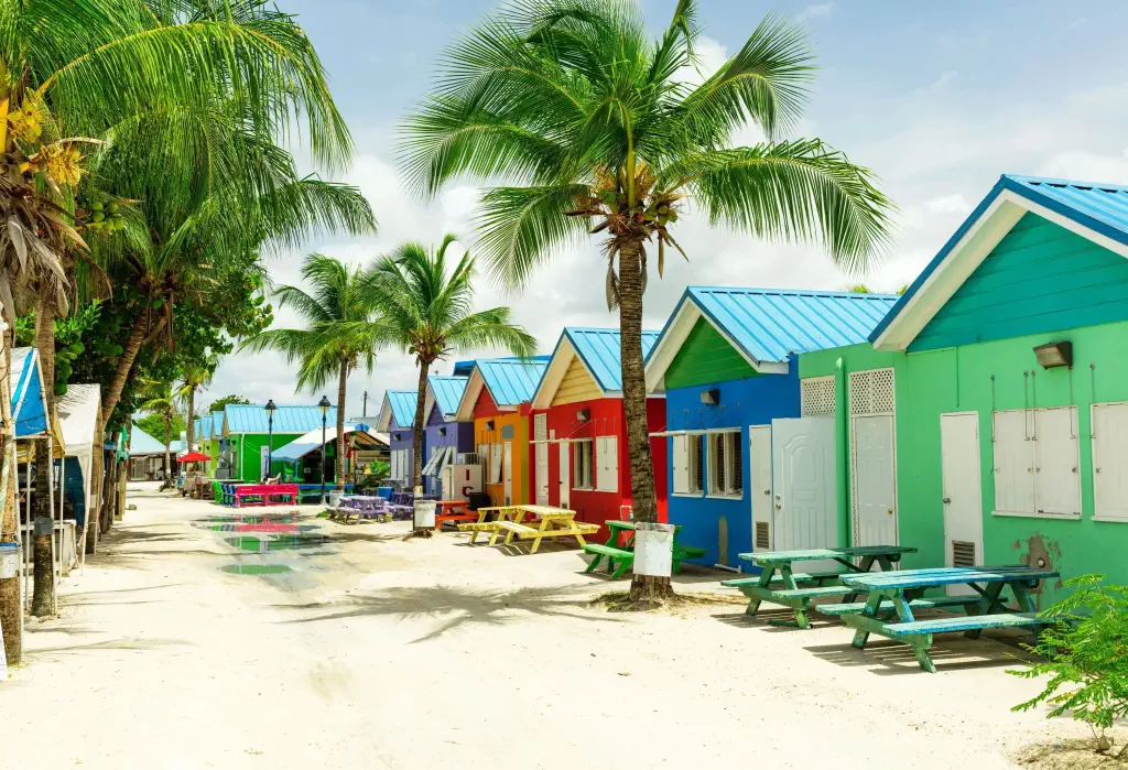 Rows of colourful houses gracefully perch on the soft white sand, while swaying palm trees dot the landscape.