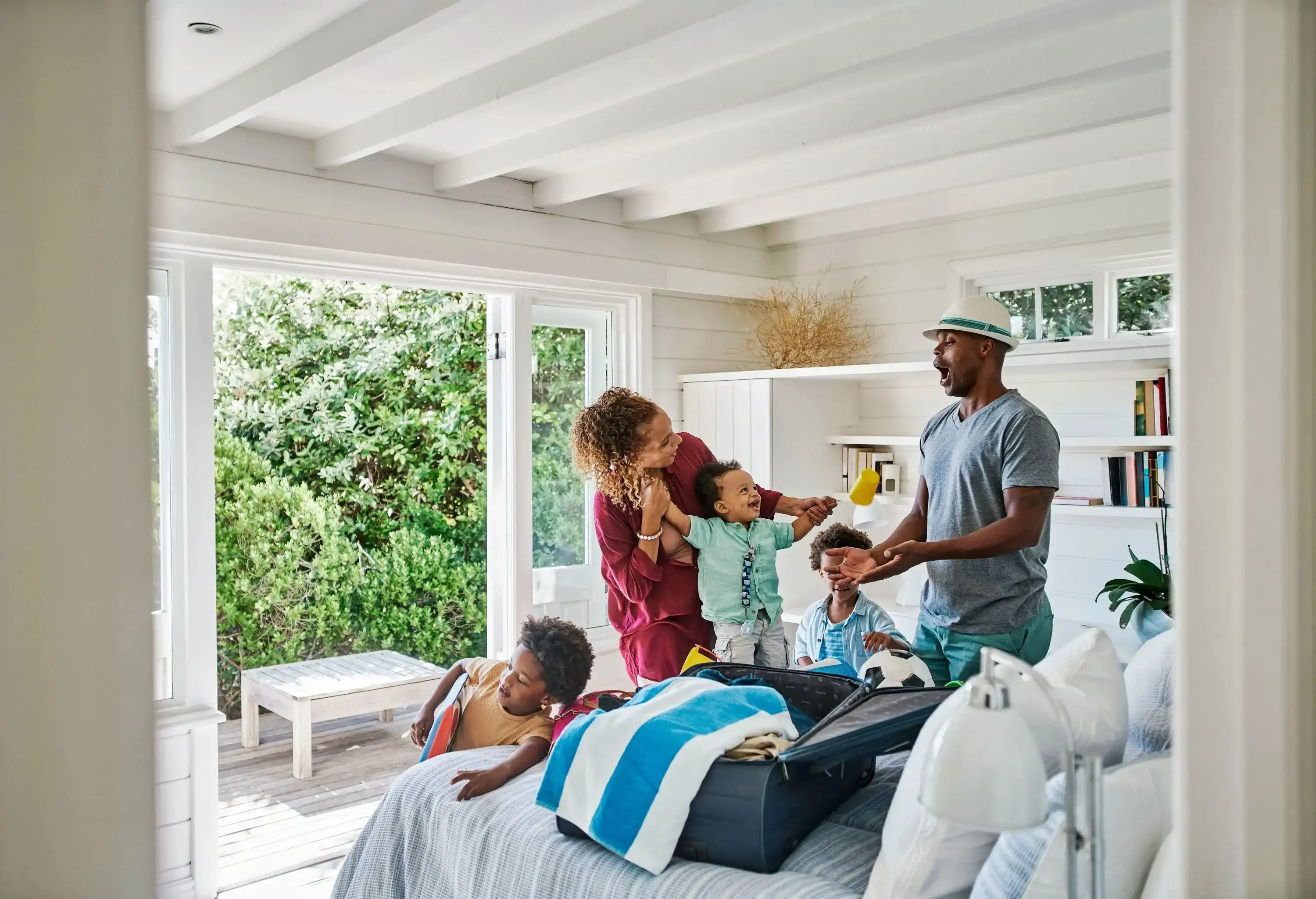 Family getting ready to travel for a trip, packing beach holiday toys in a suitcase in a home bedroom. Adorable little sons and children helping mother and father prepare for overseas vacation abroad