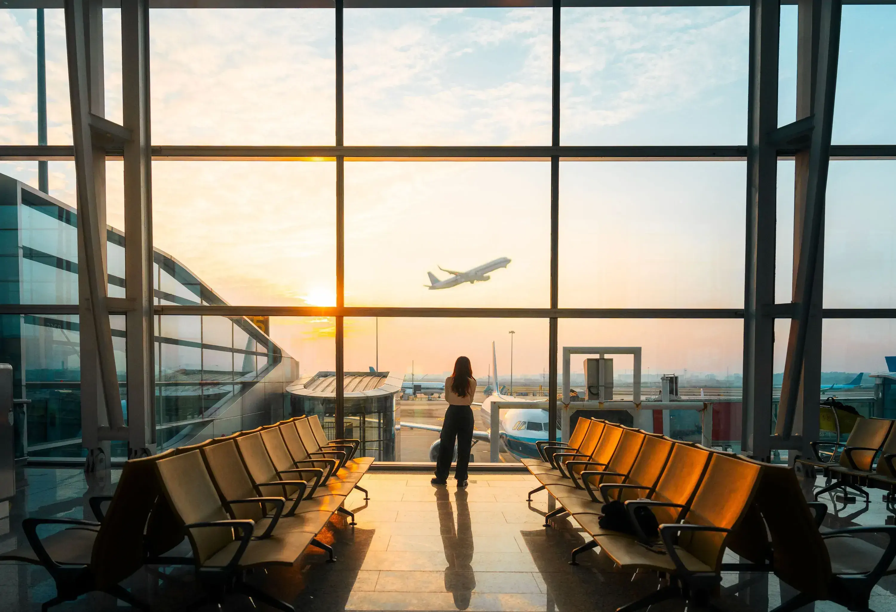 A young Asian woman is using a smartphone to check the arrival departure board and flight schedule at the airport.