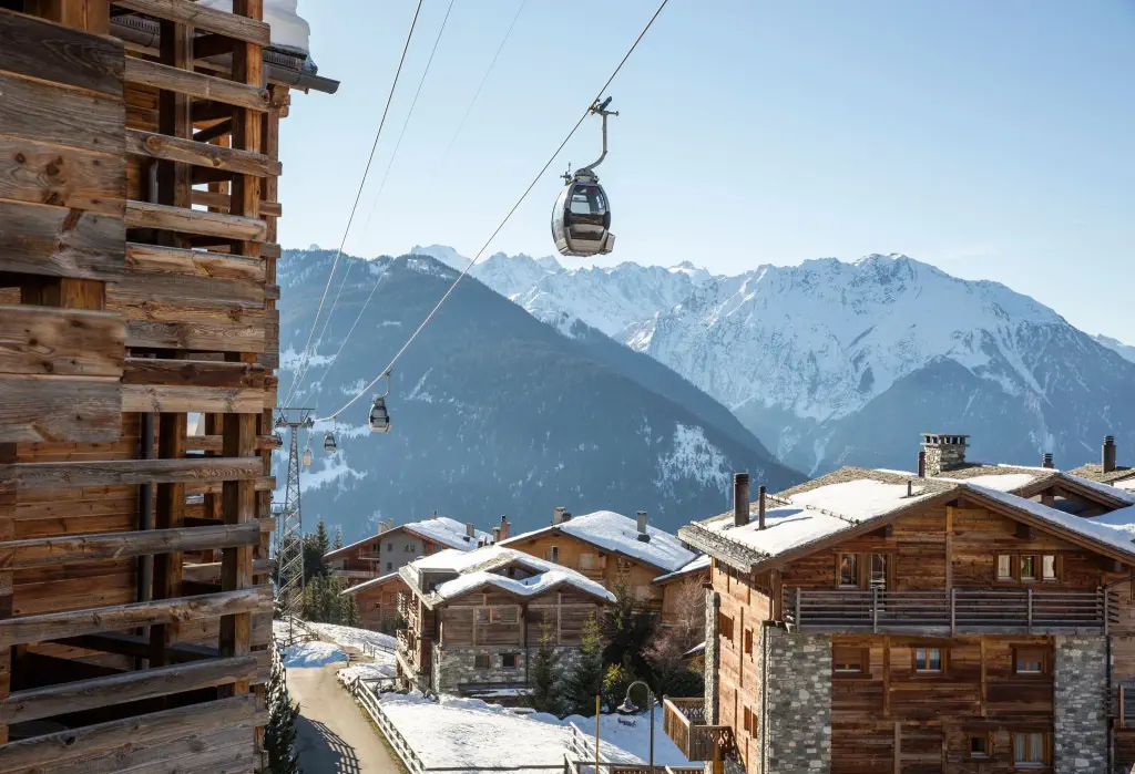 Several cable cars travel back and forth above the roofs of wooden houses.