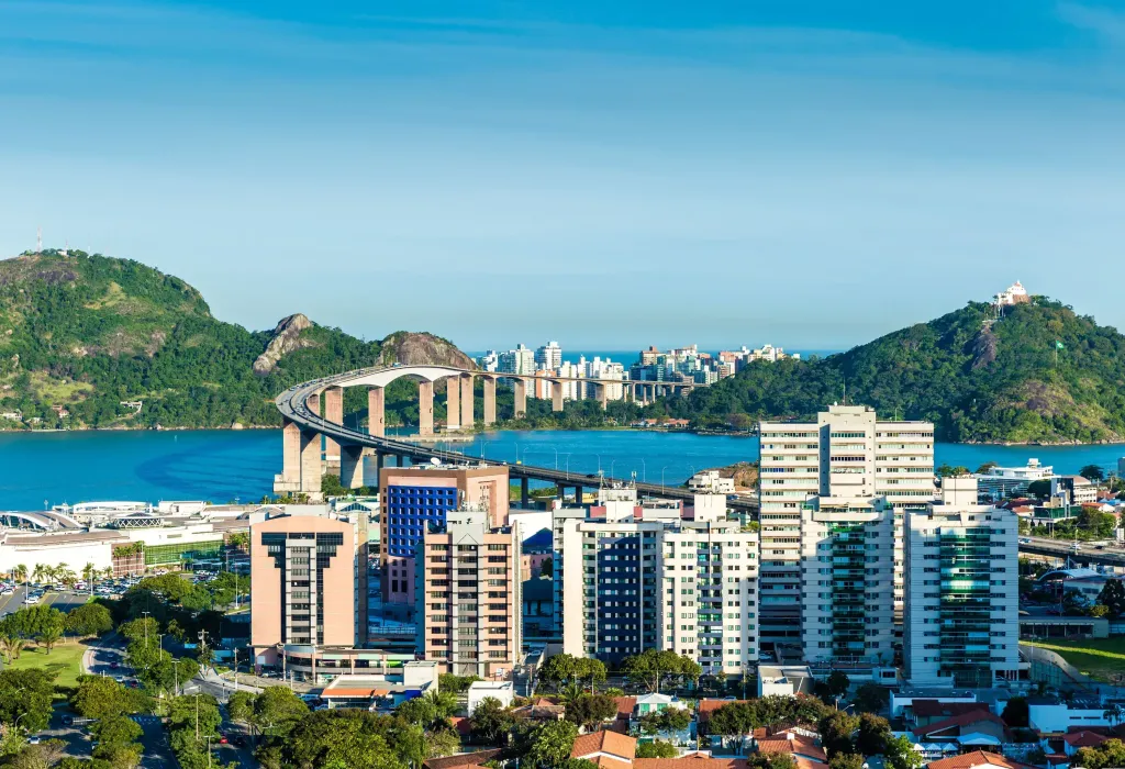 A bridge across a harbour connects two city neighbourhoods with high-rise buildings.