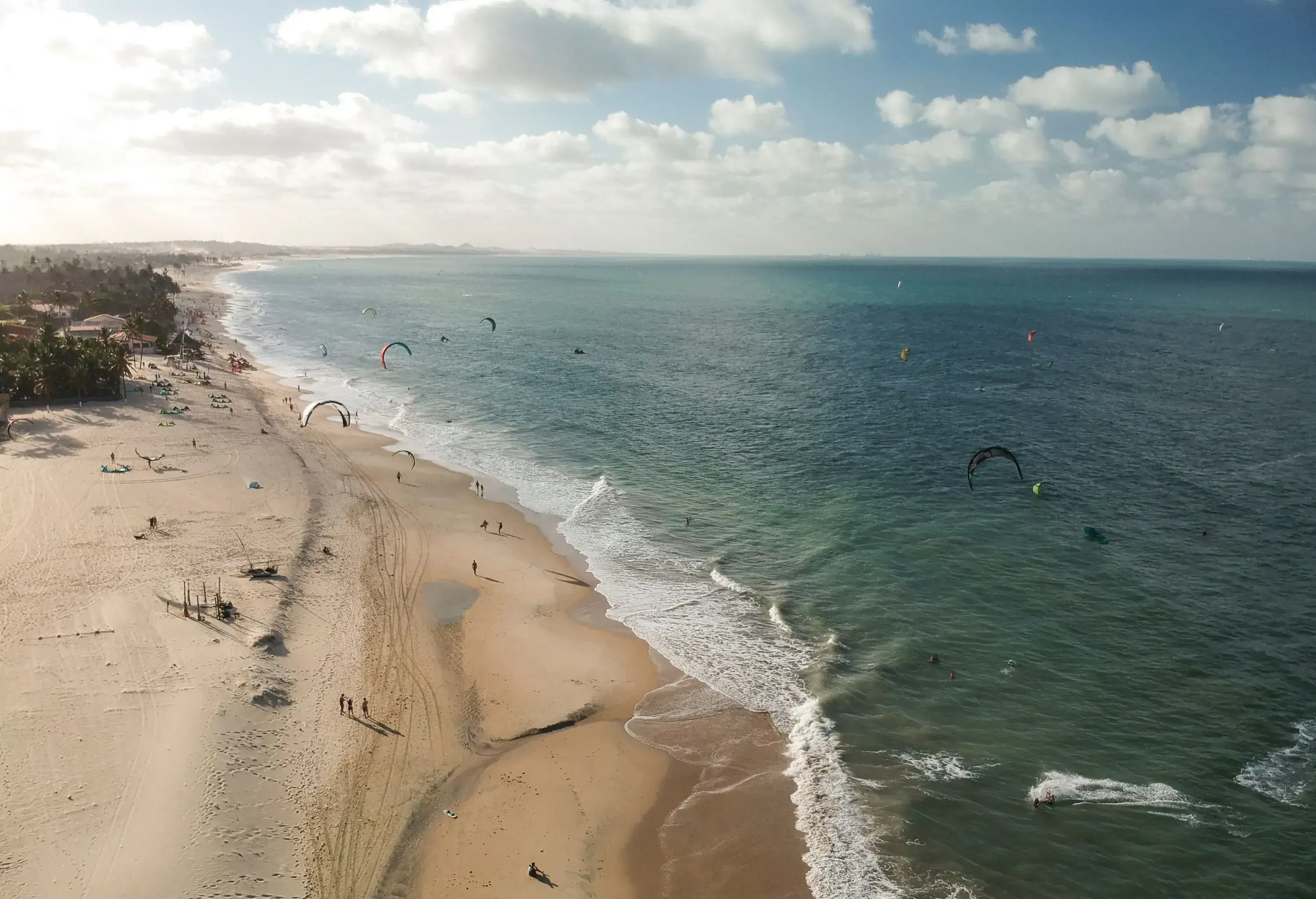A beach with people kitesurfing on an ocean's mild waves.