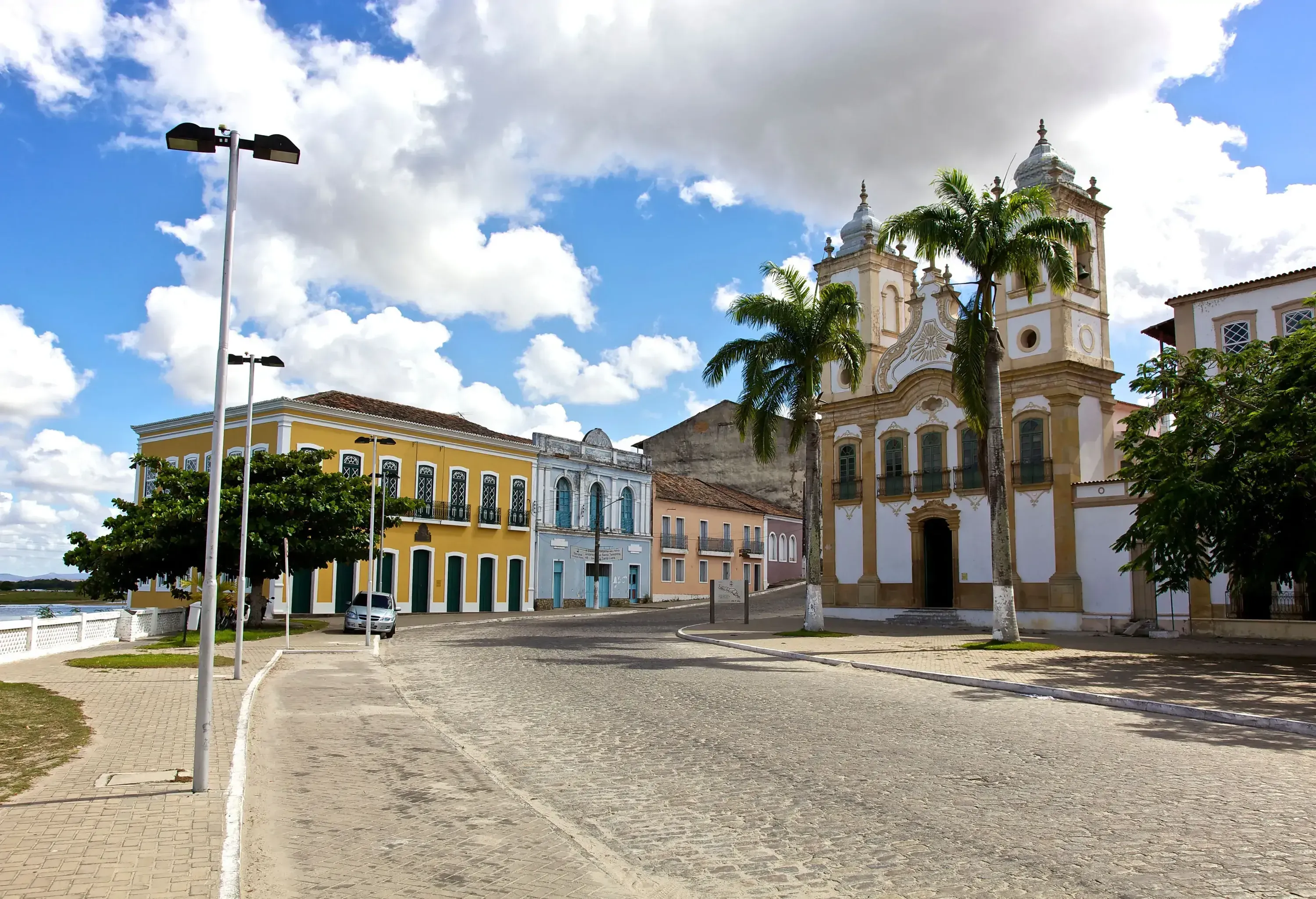 A charming brick road winds its way through a delightful collection of colourful houses, leading the eye towards a majestic church adorned with two bell towers.