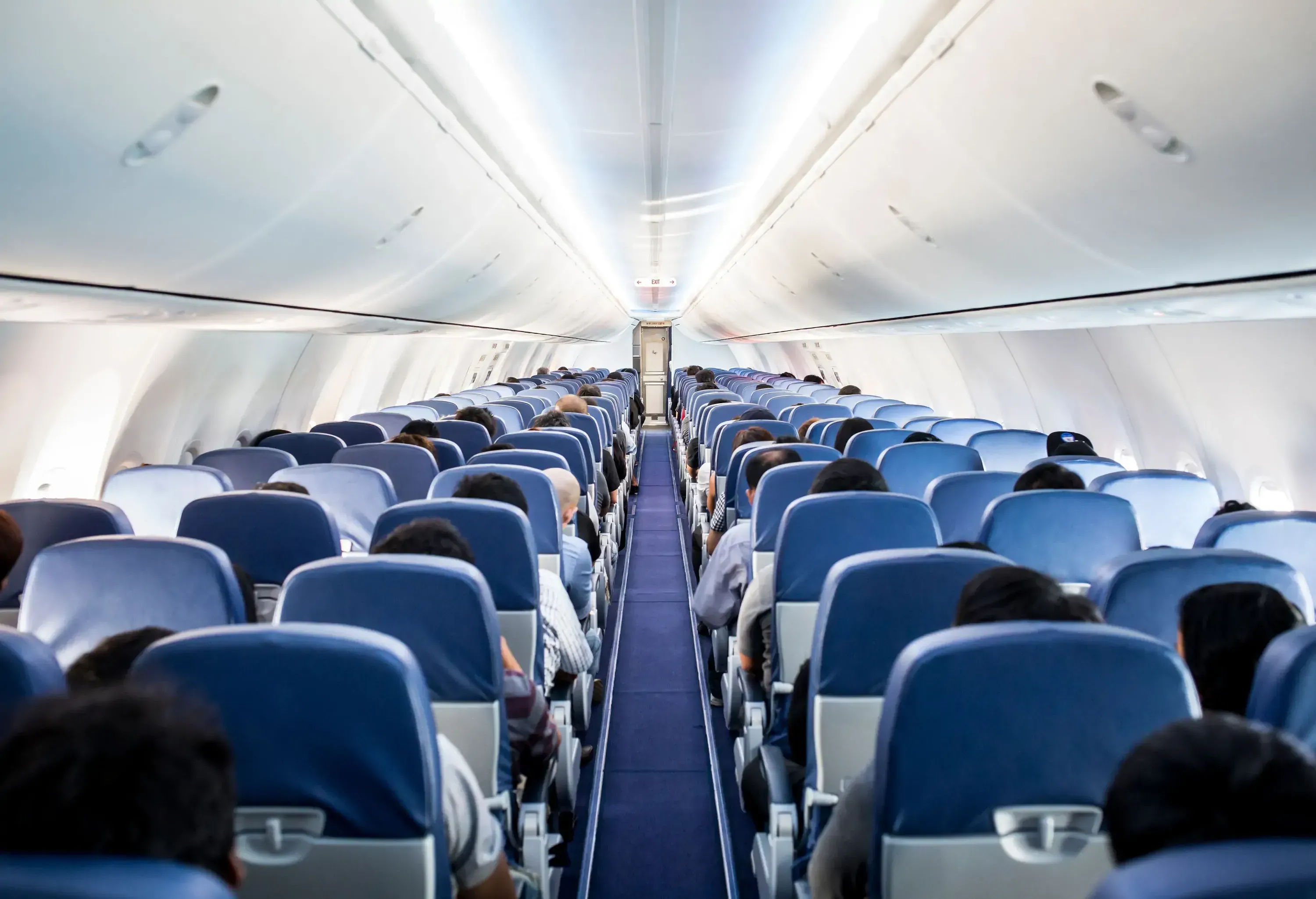 The inside of an airplane with passengers settled into their designated seats during flight.