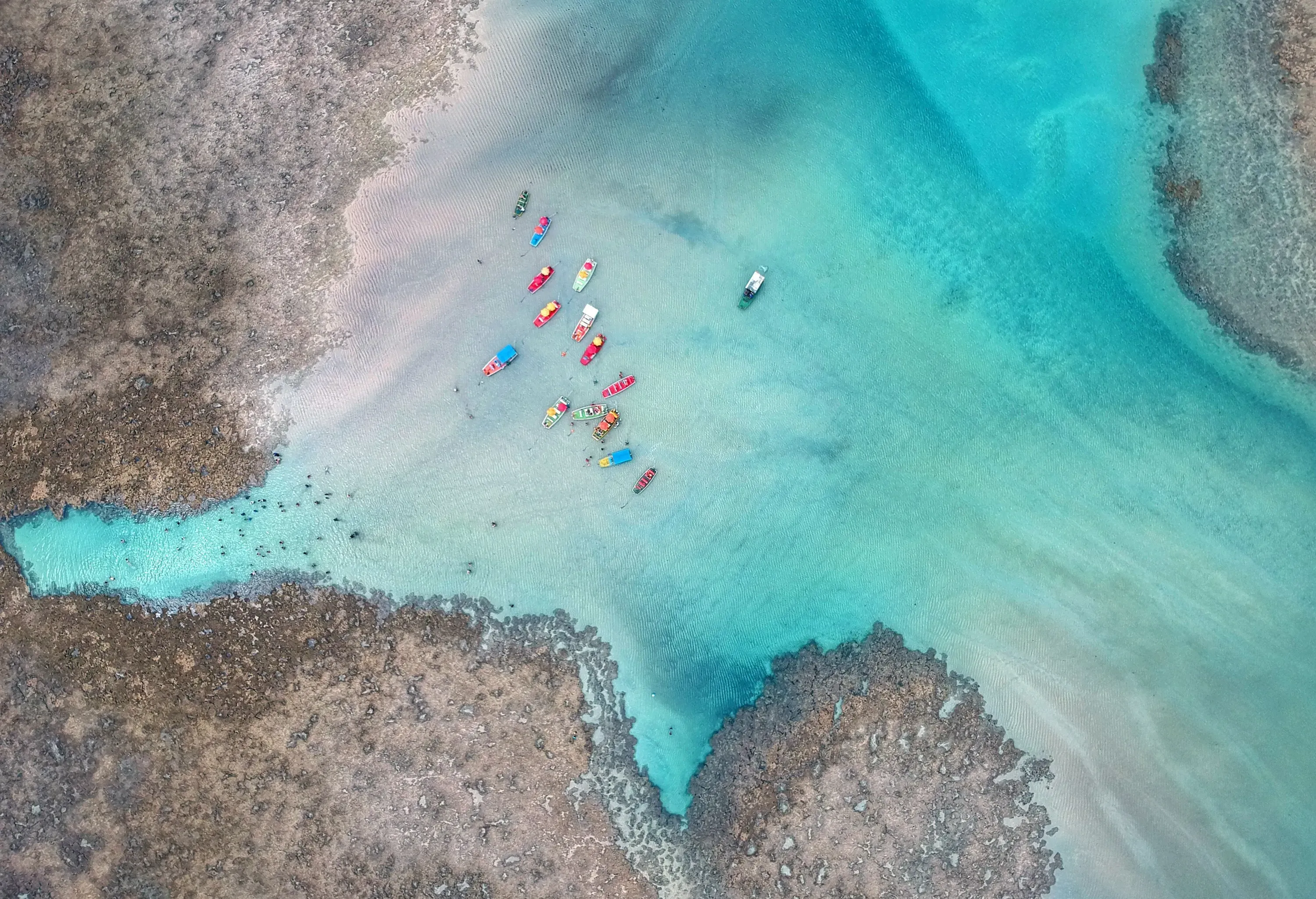 Colourful tiny boats docked on a natural pool with crystalline turquoise tranquil water.