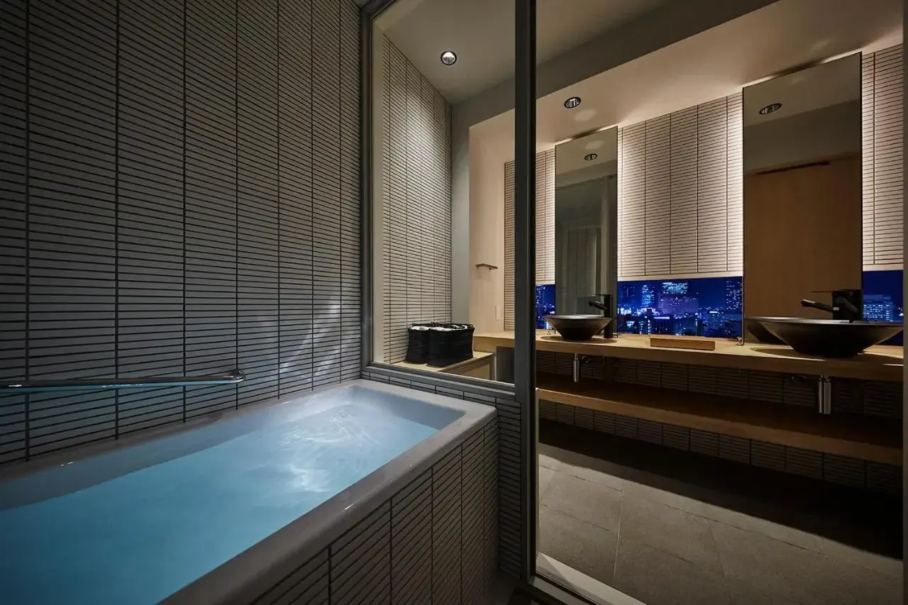 A full bathtub in a hotel bathroom with views over a cityscape