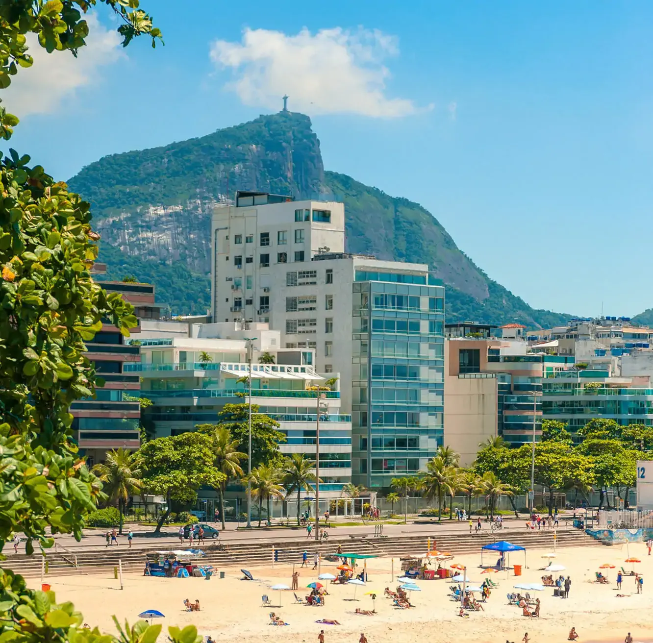 Sunny beach day in Rio de Janeiro with Christ the Redeemer overlooking the city from atop Corcovado.