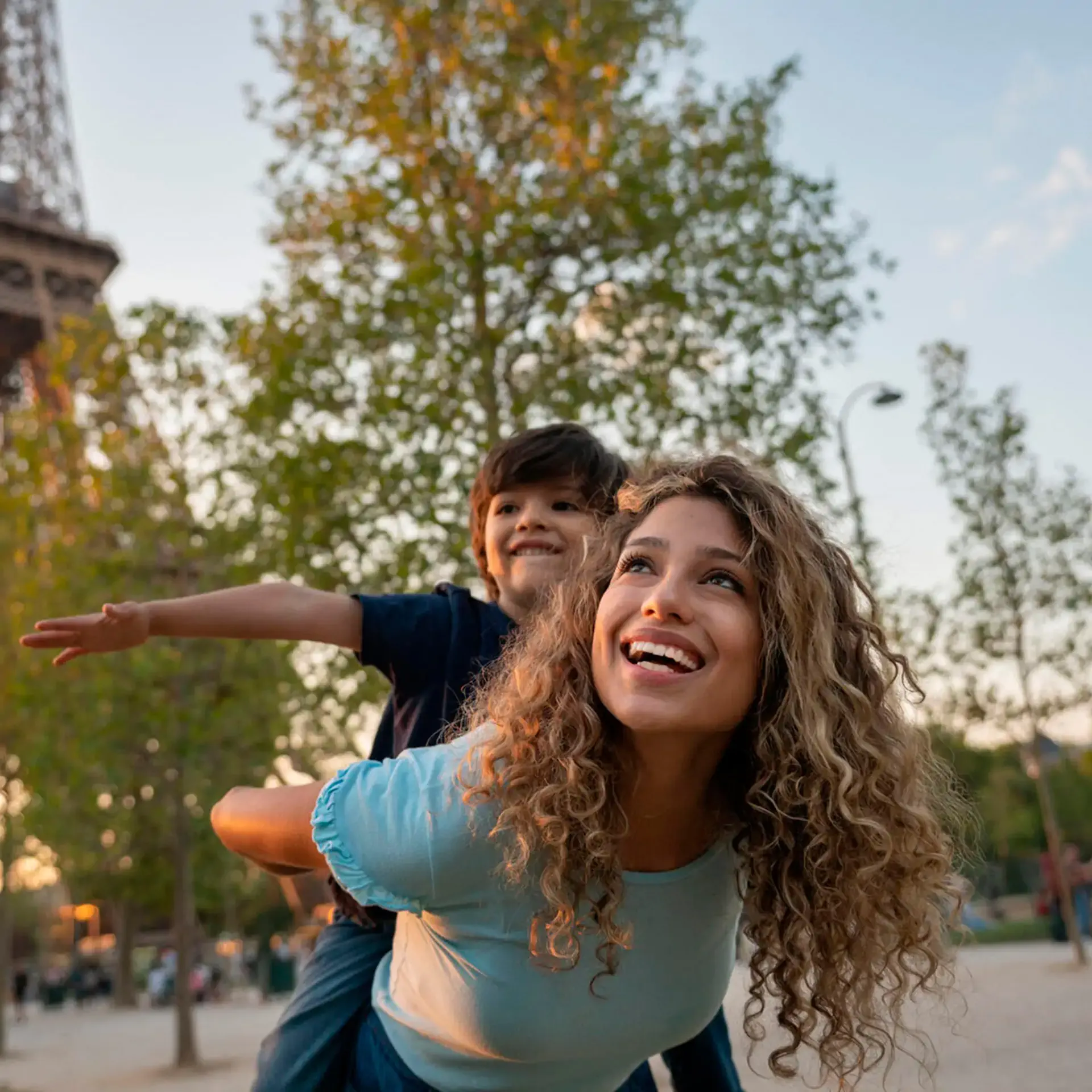 Joyful mom giving her son a piggyback ride during a sunny afternoon at the park.